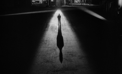 a figure standing in the shadows
