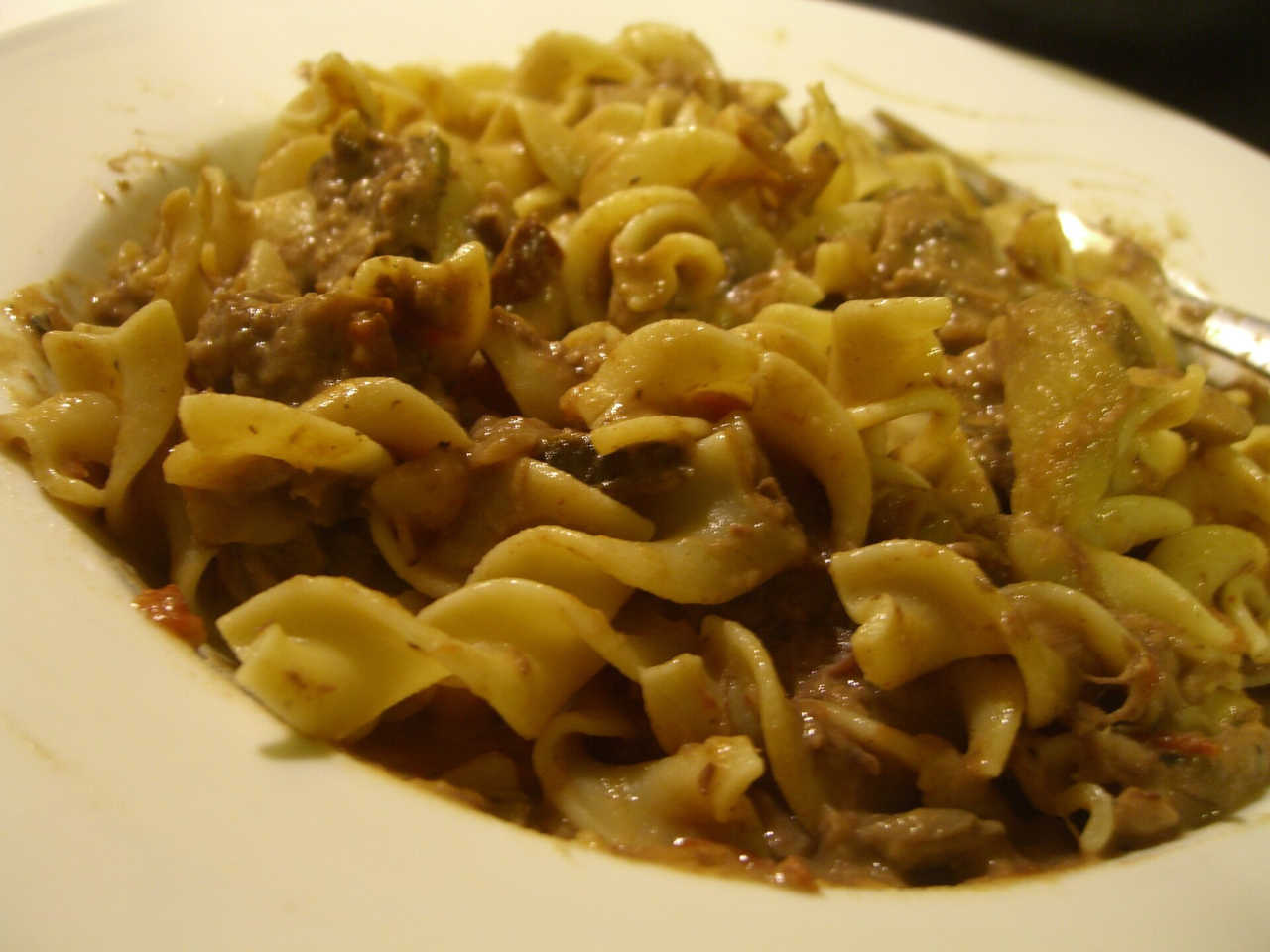 Picture of a bowl of beef stroganoff over noodles.