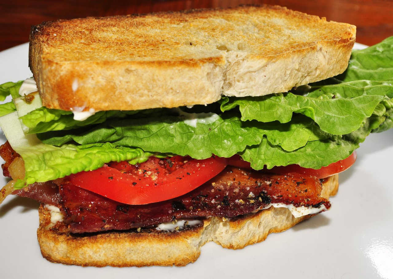 Picture of a BLT sandwich on a white plate.